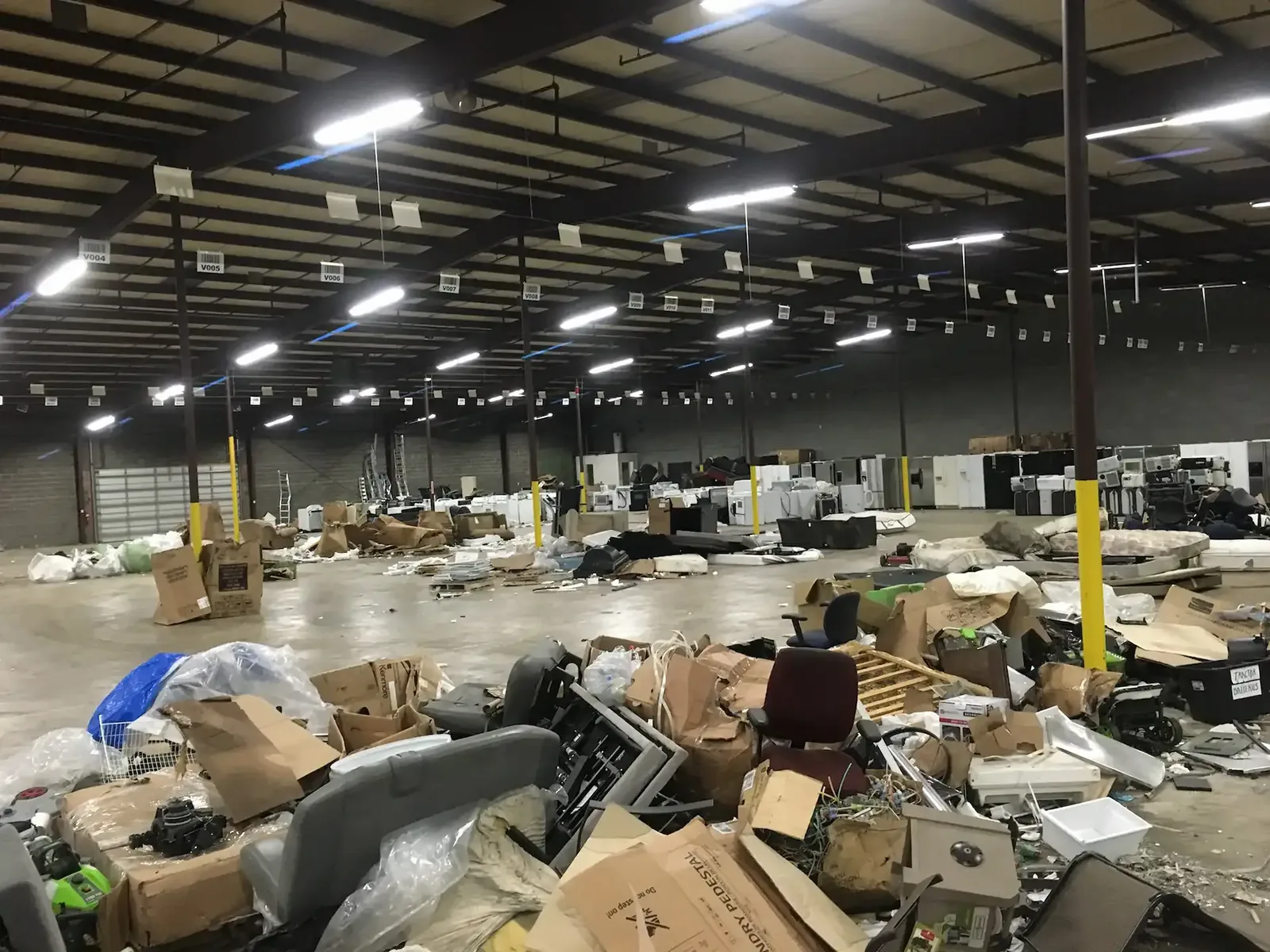 Warehouse interior filled with discarded furniture, boxes and appliances during a commercial cleanout