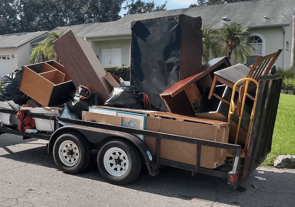 Utility trailer loaded high with cabinets, furniture and boxes hauled out during a property cleanout