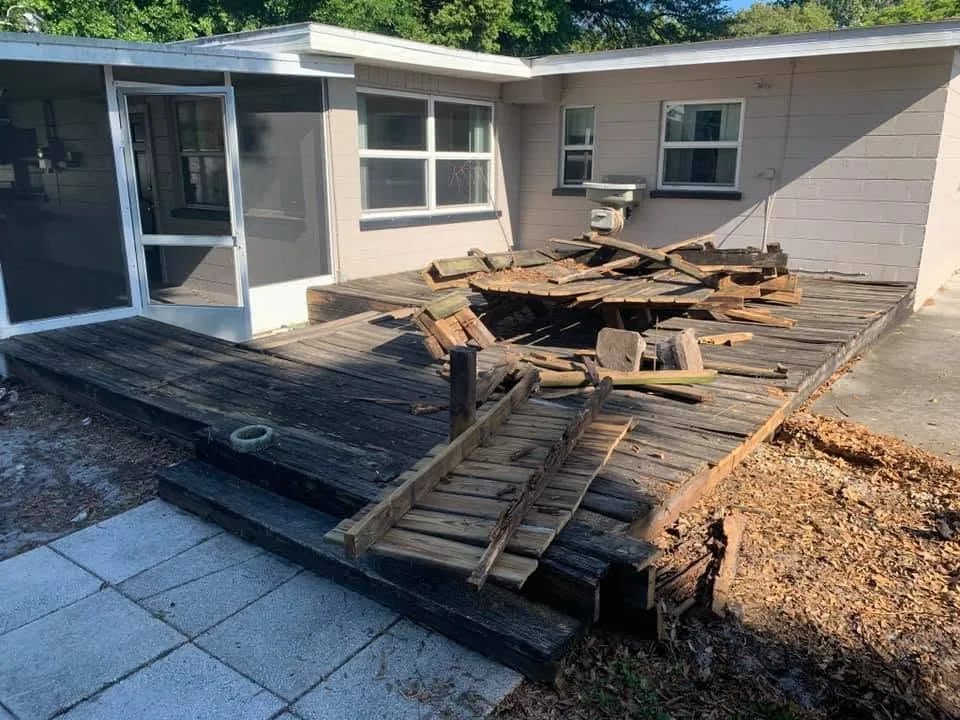 Old wood deck being torn apart behind a concrete block house