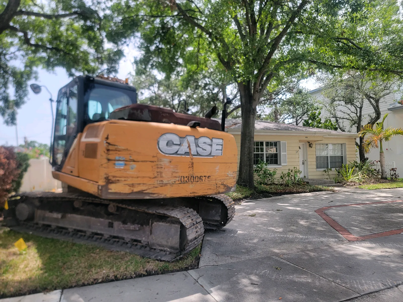 Excavator staged in front of a house before demolition